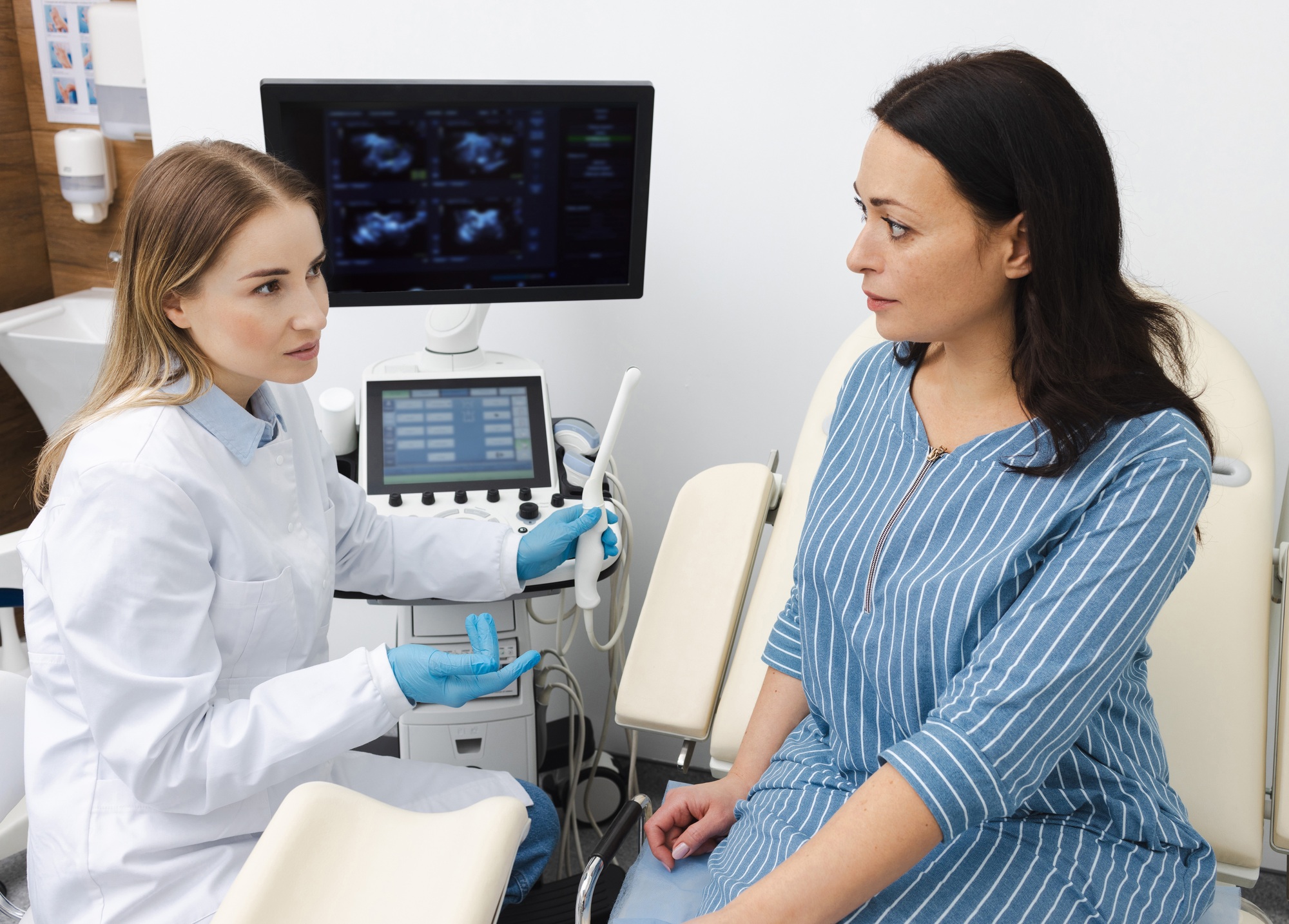 Doctor with ultrasound transvaginal sensor for ultrasound procedure to female patient in medical