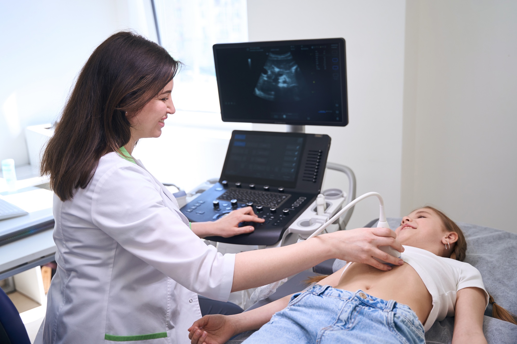Female conducts an ultrasound of internal organs of little girl
