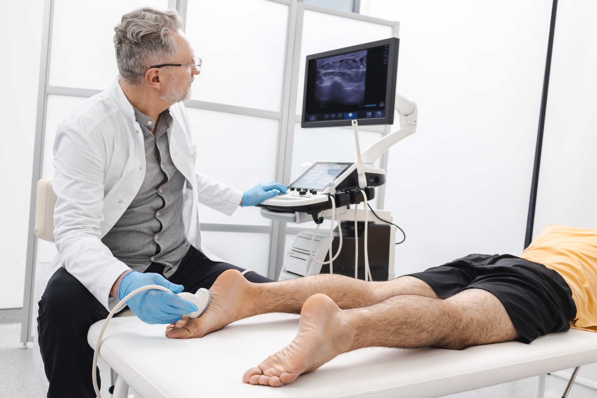 Man having foot with pain scanned using modern ultrasound machine. Ultrasound of foot and leg