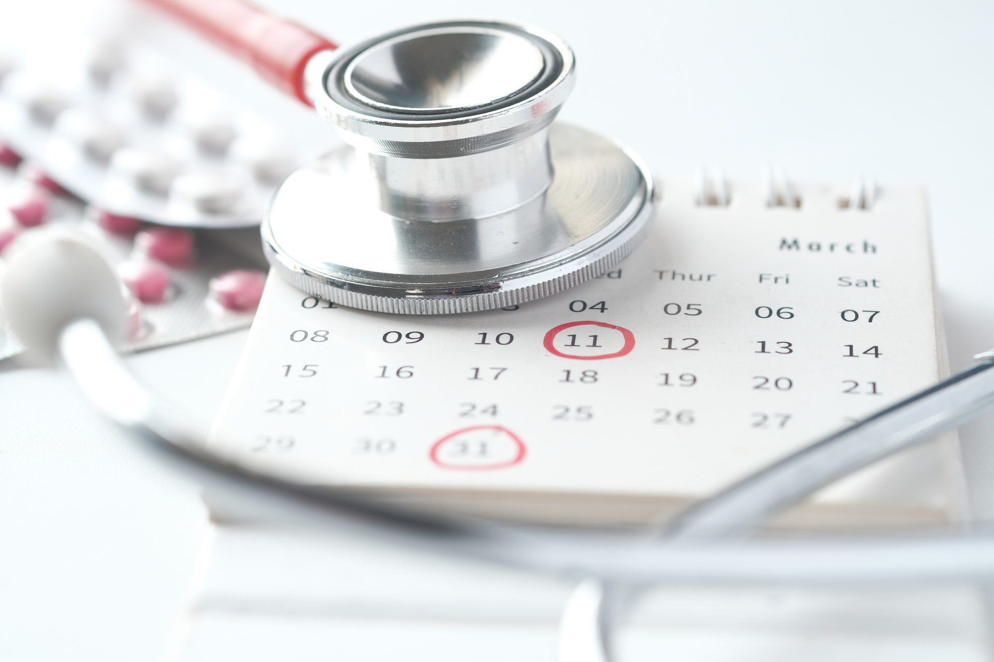 medical pills and stethoscope on calendar on white background