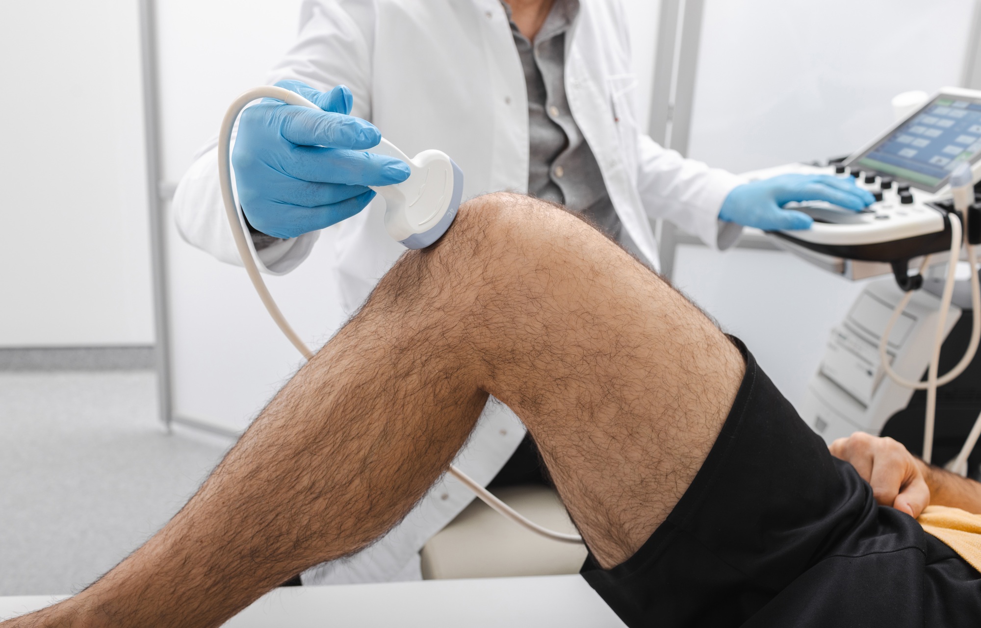 Sonography of knee joint. Male patient with knee injury during knee ultrasound with professional